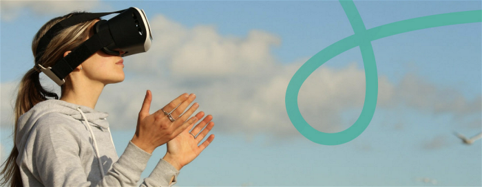 Fotografi av en kvinna som har på sig ett VR-headset och höjer armarna i skyn.