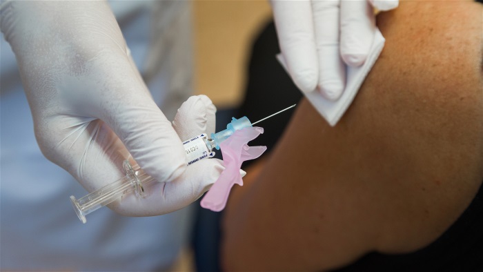 En person får en spruta med vaccin i sin överarm.