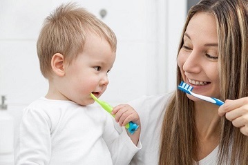 Barn och förälder som borstar tänderna