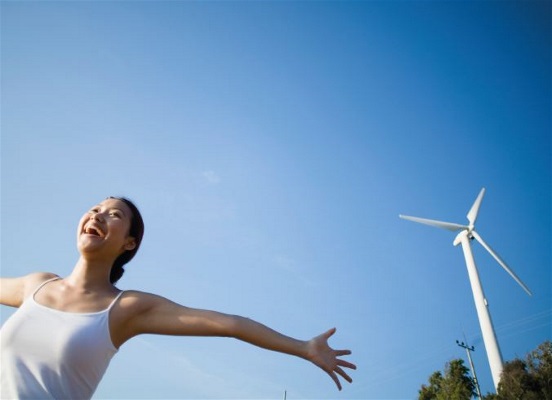 Bild på en kvinna med vindkraftverk i bakgrunden