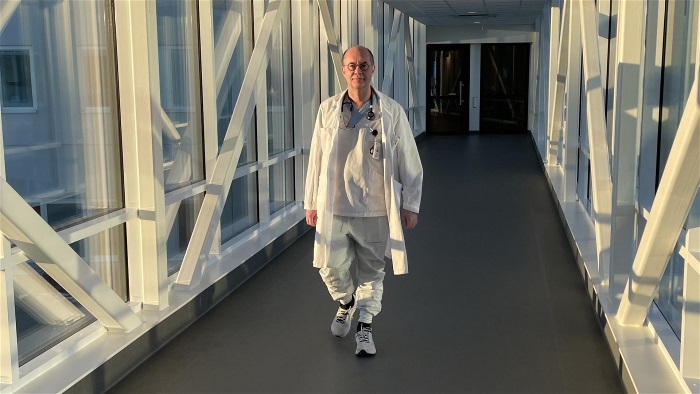Person i läkarrock går över skywalk. 