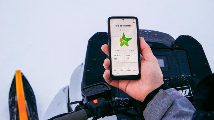 Mobiltelefon med app som hålls i av en person som sitter på en snöskoter